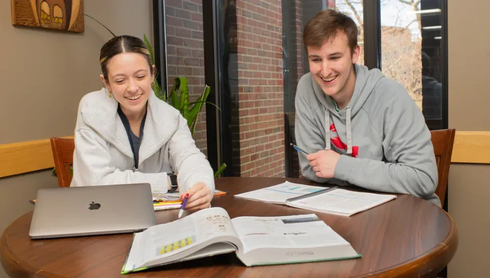 Two students studying together with an open book in front of them